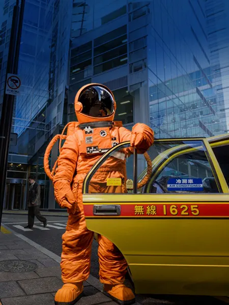 Astronaut in orange suit, getting out of a cab in city with skyscrapers
