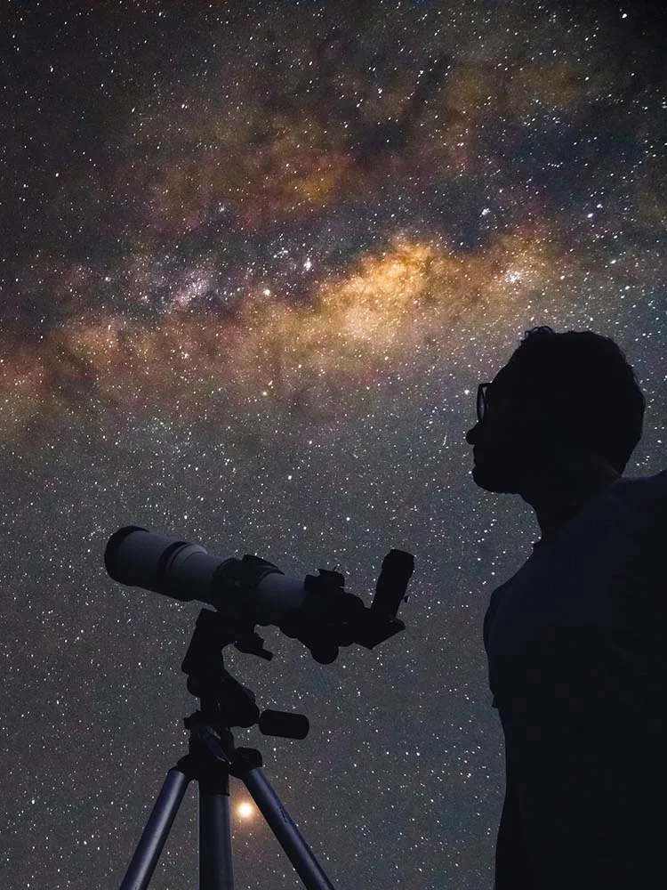 Man with telescope looking at stars and galaxy