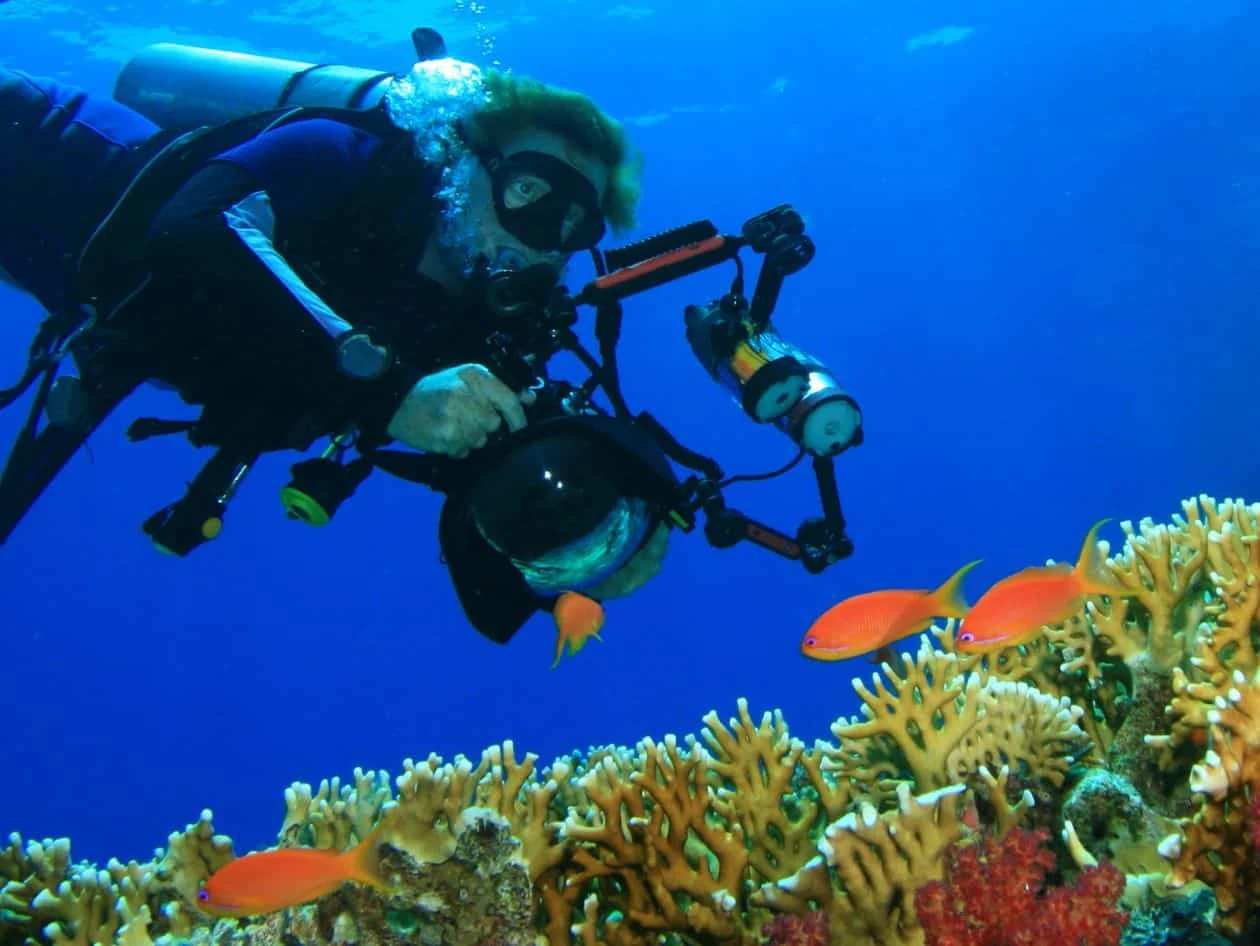 Underwater marine biologist photographer taking a photo of the fish and coral reef